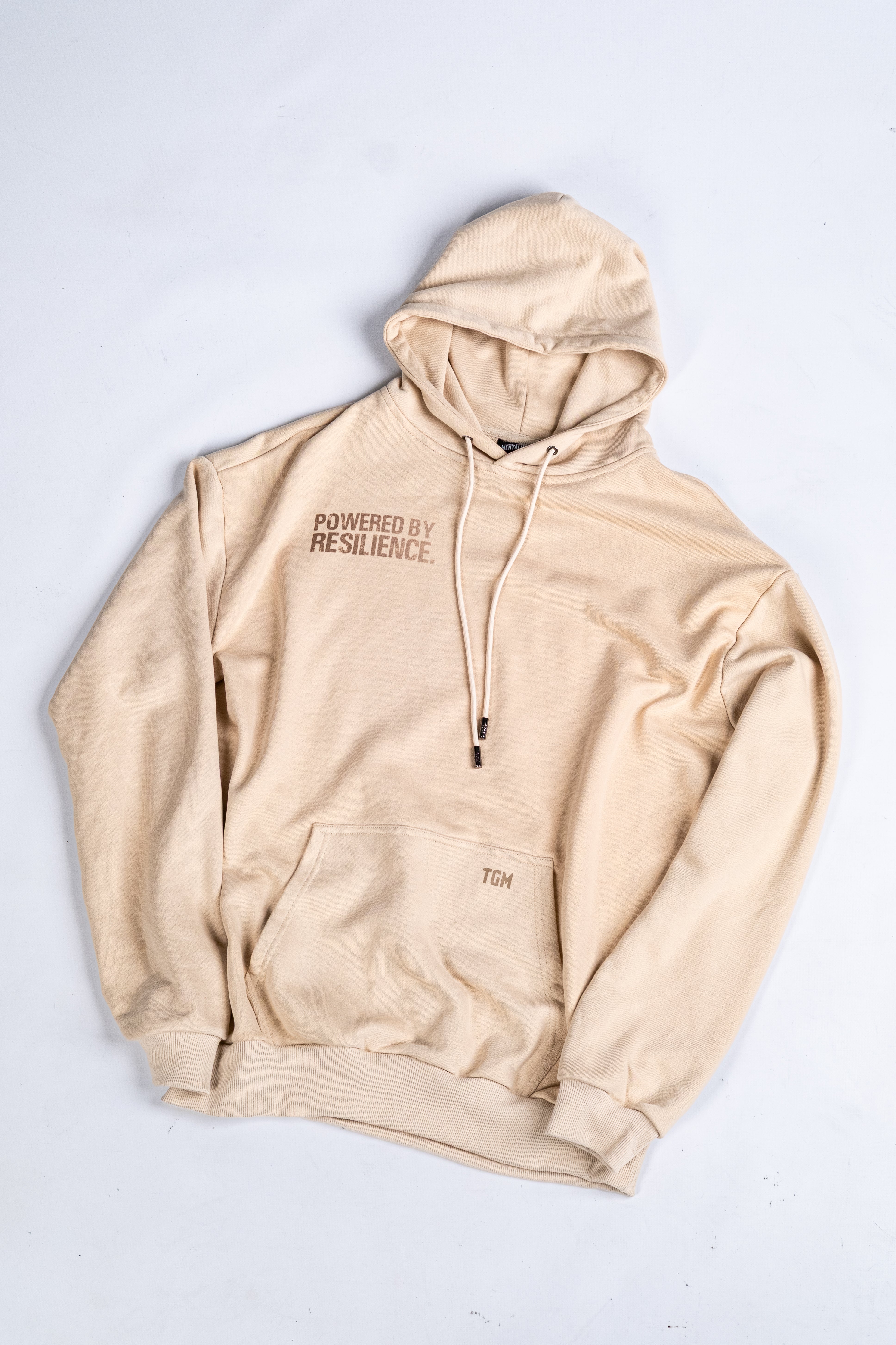 Beige Oversized Hoodie with brown gradient text saying powered by resilience. 100% premium cotton