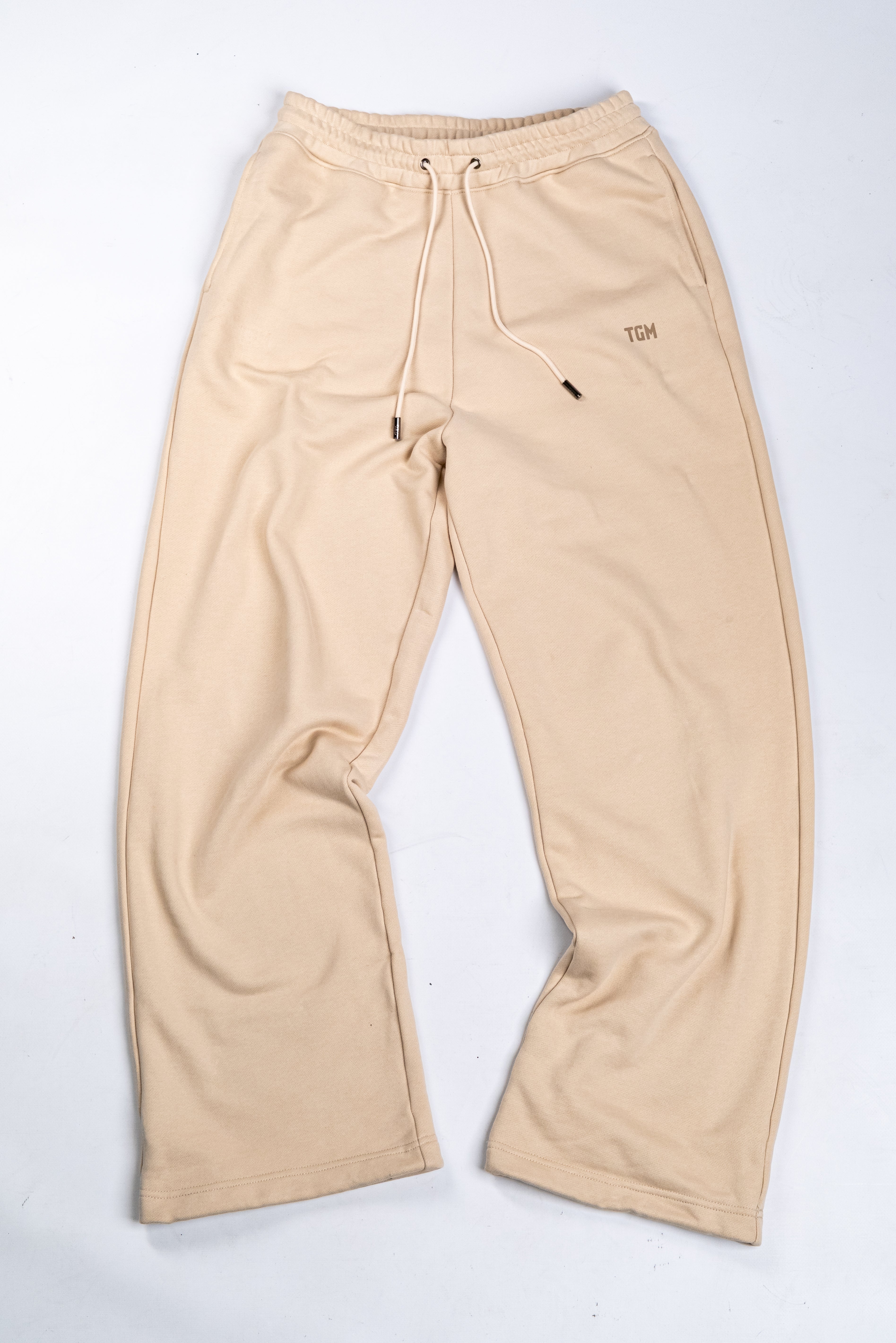 Beige sweatpants with a TGM brand logo on the left leg