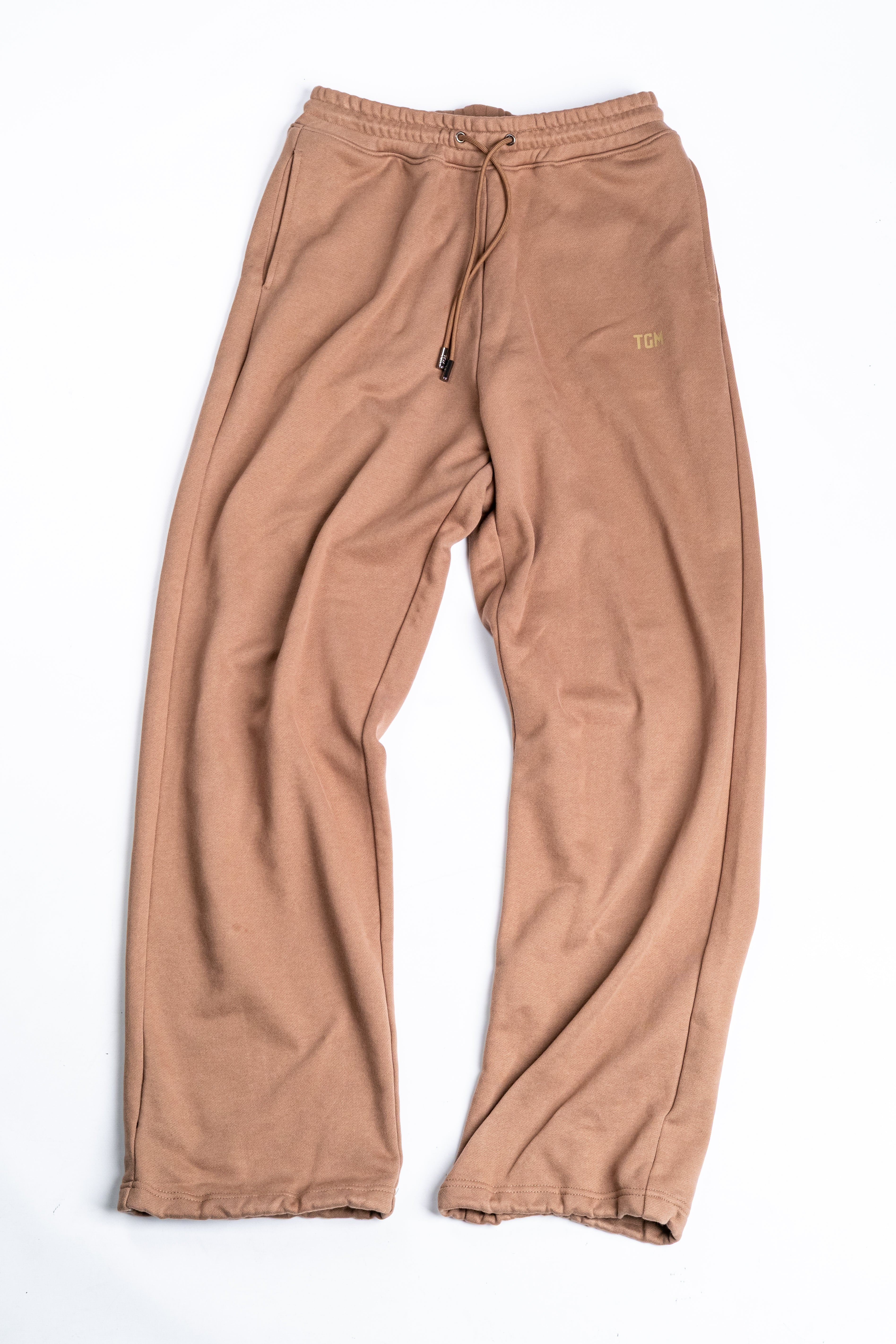 Brown sweatpants with a TGM logo on the left leg