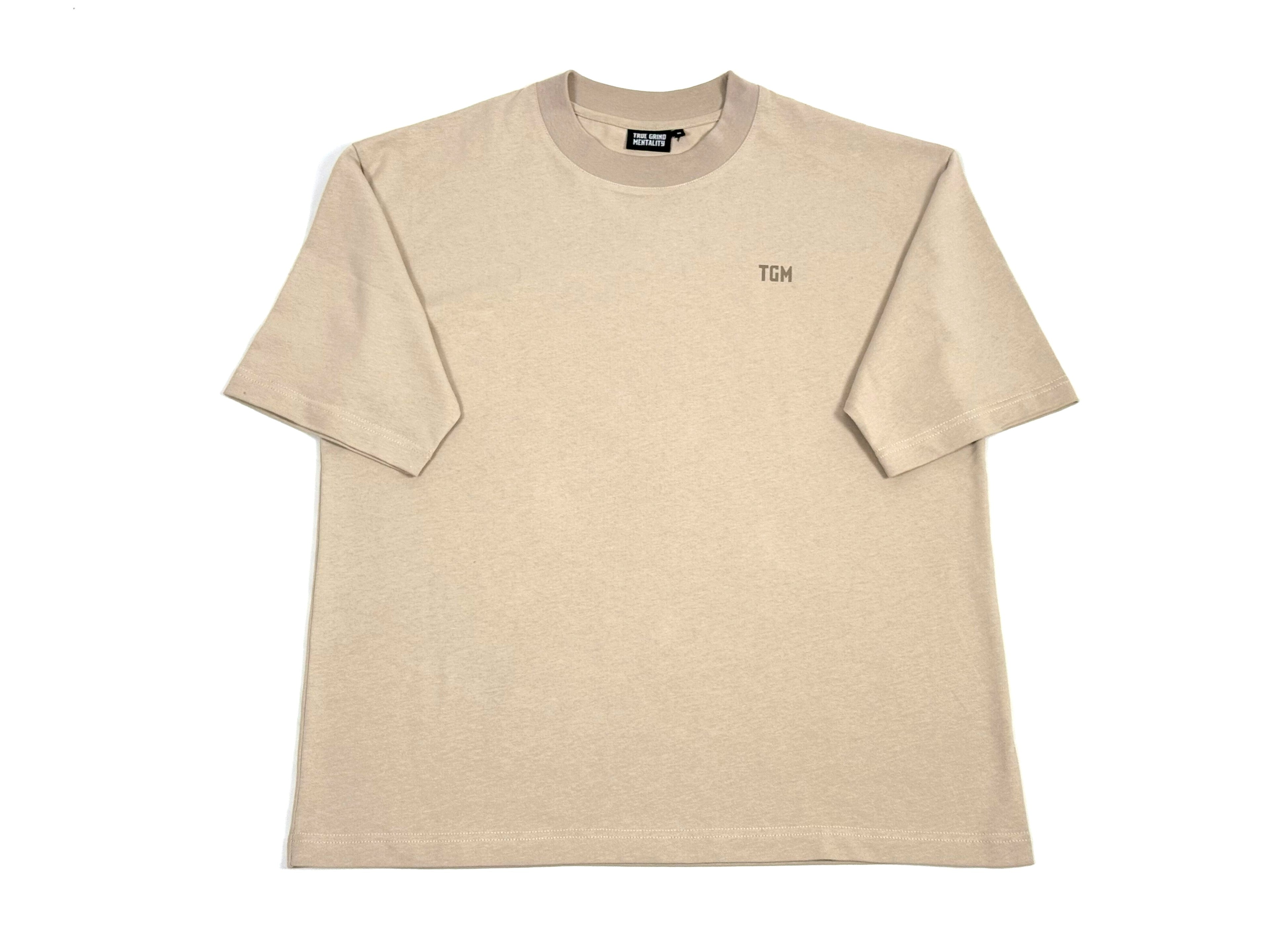 A beige box fit t-shirt with a TGM logo on the left side of the chest.